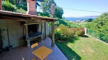 A patio with a stone fireplace, a table, and chairs.