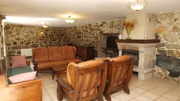 A stone-walled living room with a fireplace, leather sofas, and a television.