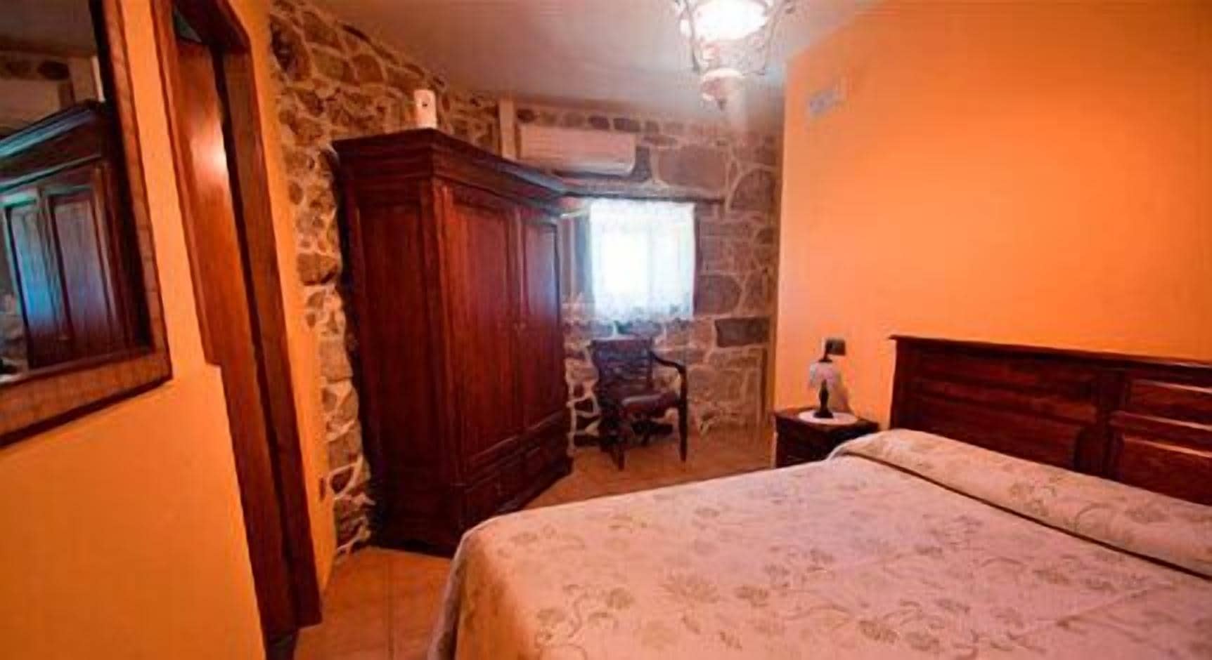 Un dormitorio con cama, un armario de madera, una silla y una mesita de noche.