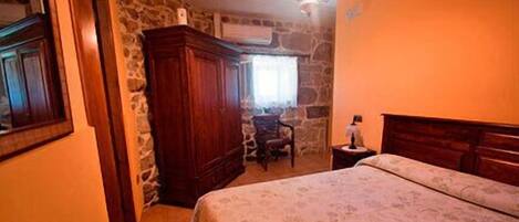 Un dormitorio con cama, un armario de madera, una silla y una mesita de noche.