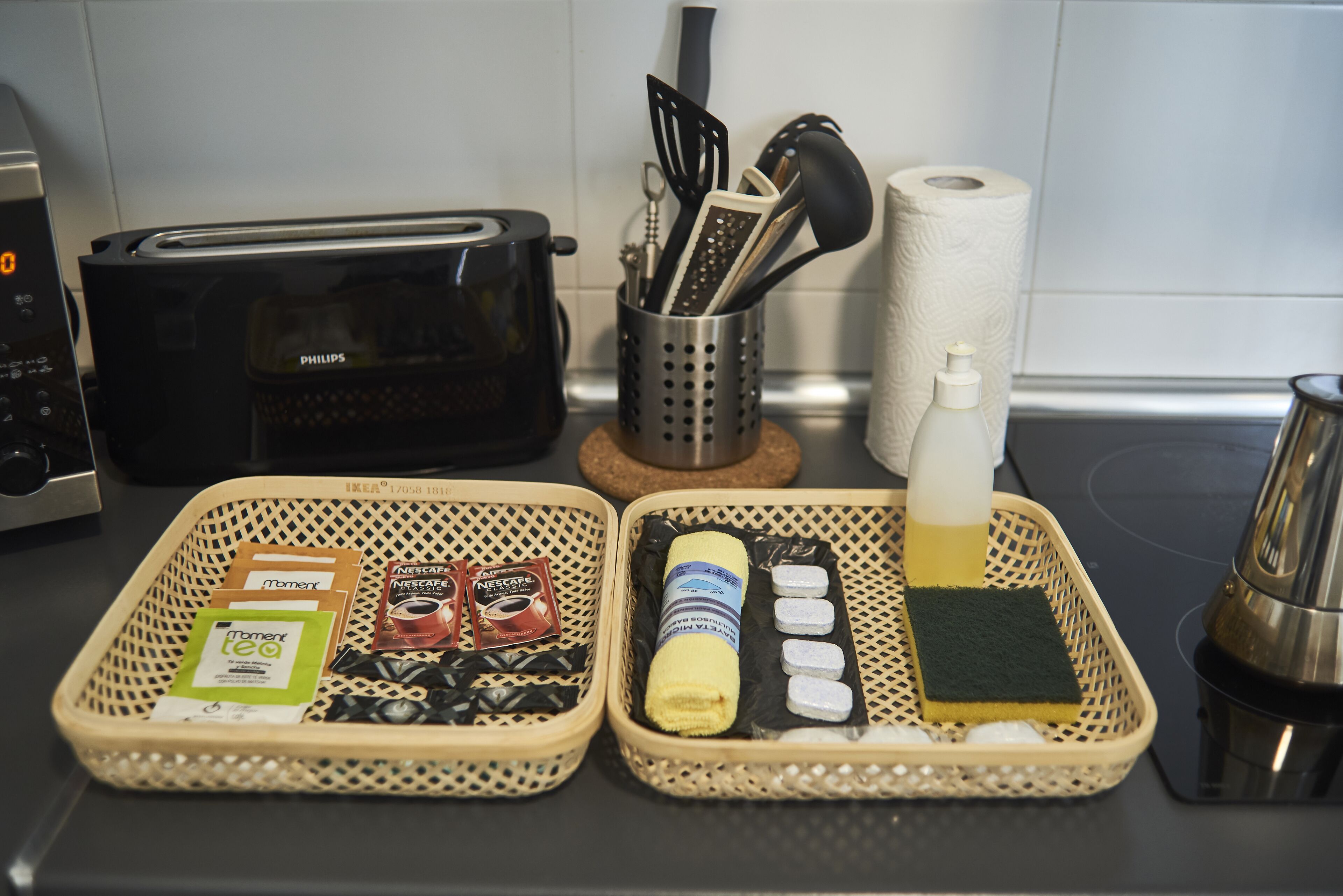 A kitchen counter with a toaster, a coffee maker, a basket with coffee pods, a sponge, and a bottle of dish soap.