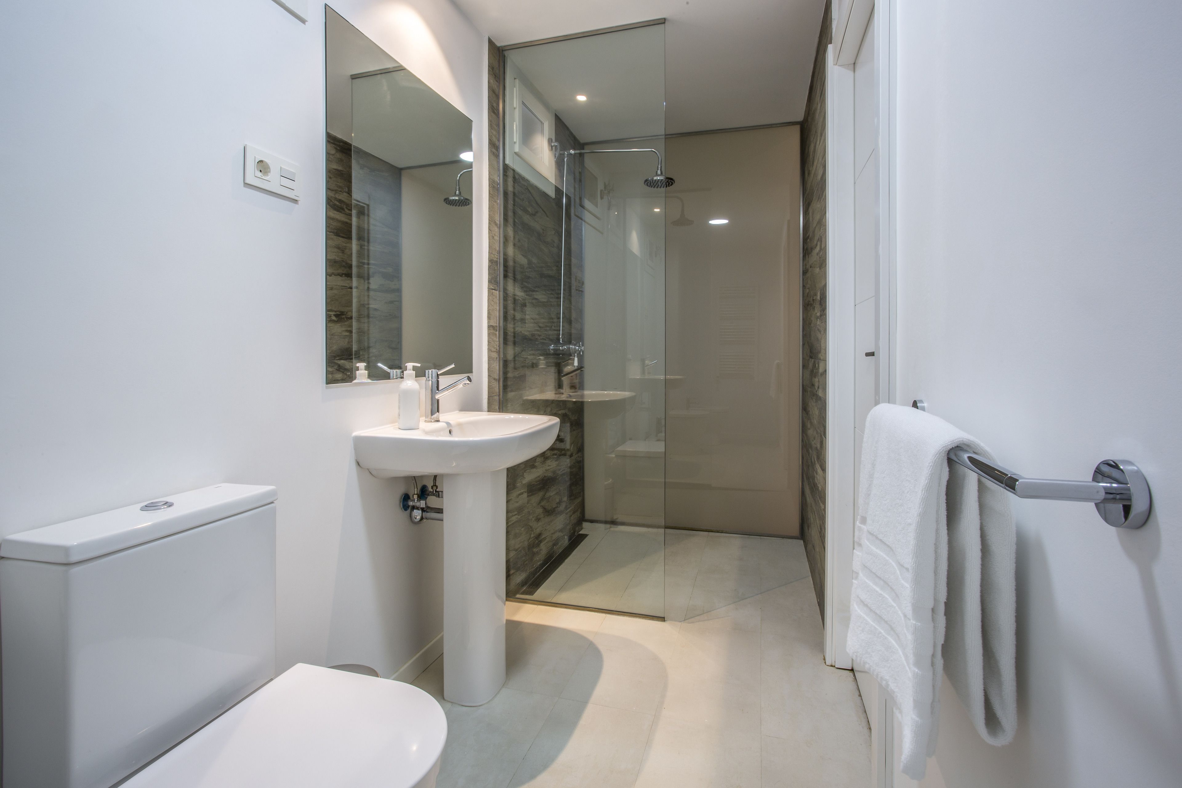 Een moderne badkamer met toilet, wastafel en douchecabine.