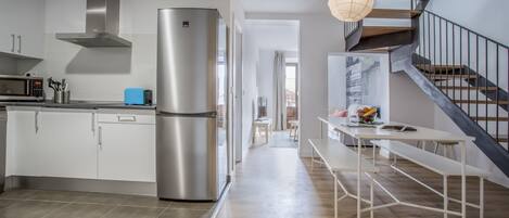 Eine moderne Küche mit einem Edelstahl-Kühlschrank, weißen Schränken und einer Holztreppe.