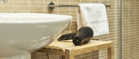 A bathroom with a sink, a wooden shelf with towels, and a towel hanging on a rack.