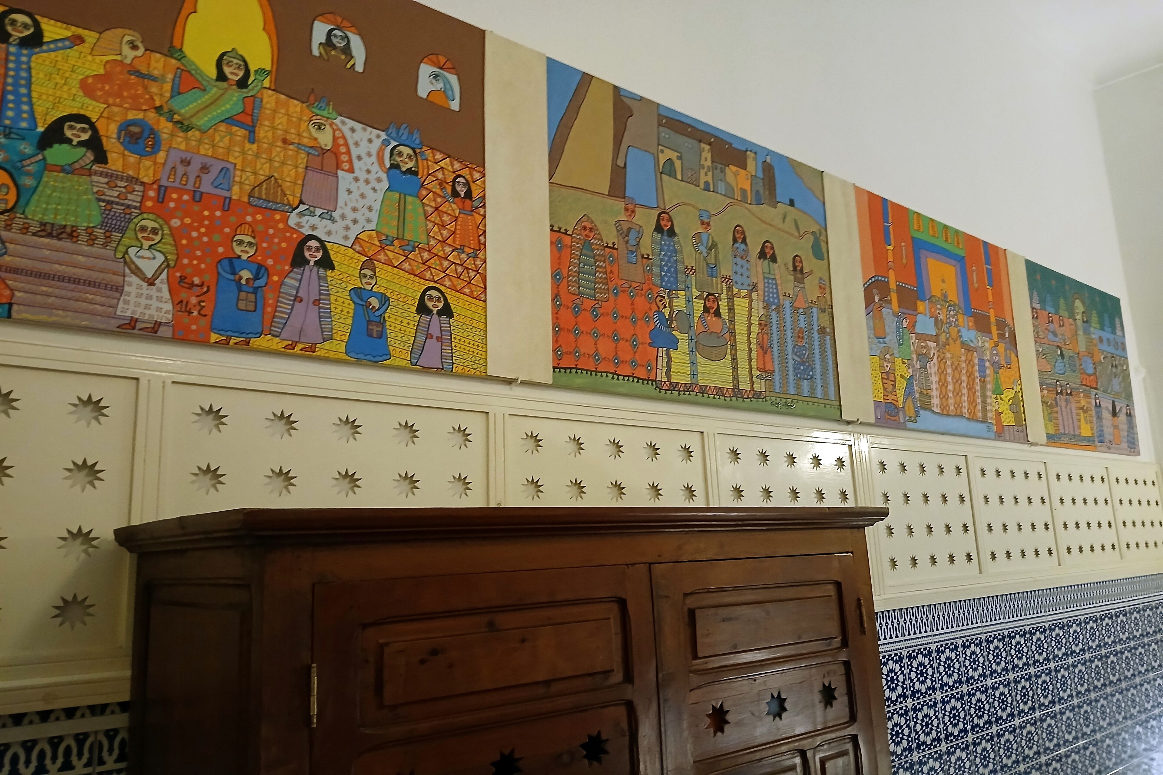 A wall with three colorful paintings depicting various scenes.