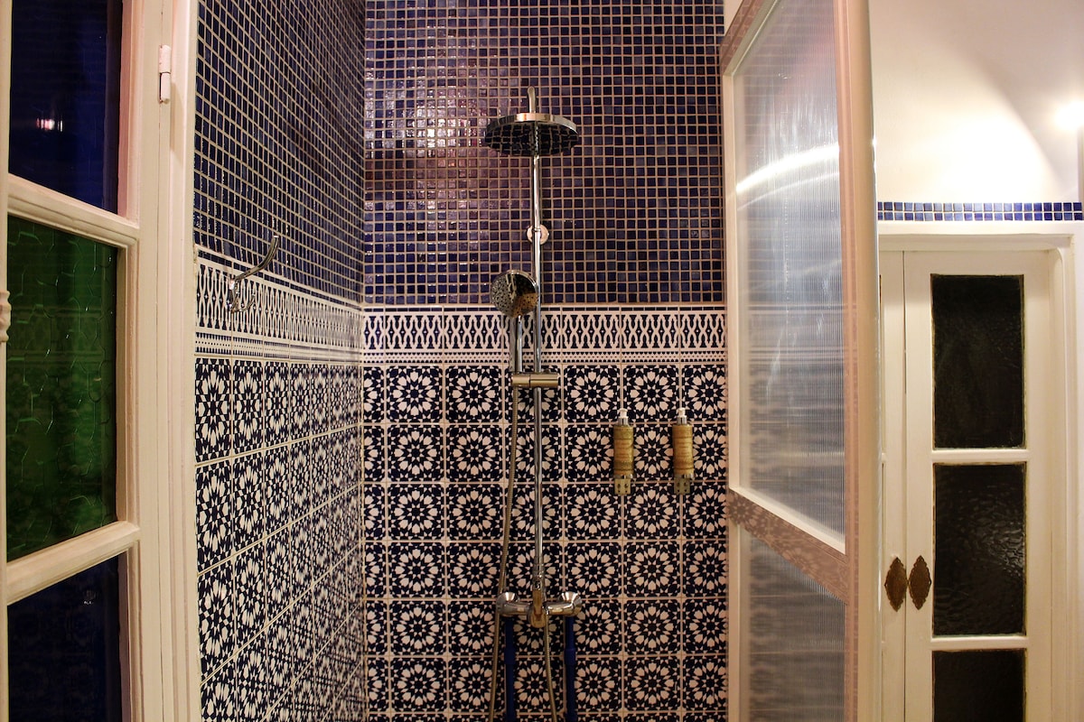 A bathroom with a shower, tiled walls, and a door with glass panels.