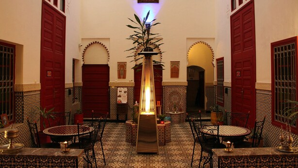 A traditional Moroccan interior with a central fountain, patterned tiles, and red doors. - Riad Meftaha (Rabat)