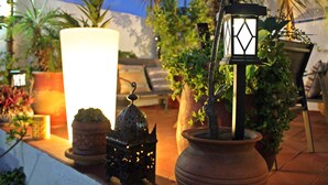A patio area with potted plants, a large white candle, and decorative lanterns. - Riad Meftaha (Rabat)