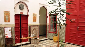 A traditional Moroccan interior with red doors, tiled floors, and a potted plant. - Riad Meftaha (Rabat)