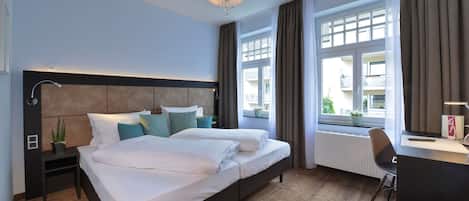 Habitación de hotel con una cama grande, un escritorio y una ventana con cortinas.