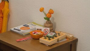 A table with a book, a bowl of snacks, a chessboard, and a vase with flowers.