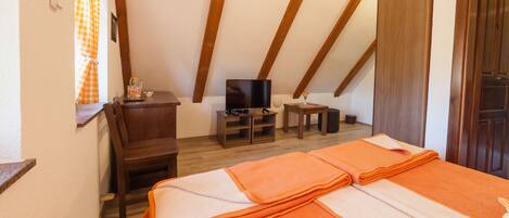 Una habitación con cama, televisión, una mesita y una silla.