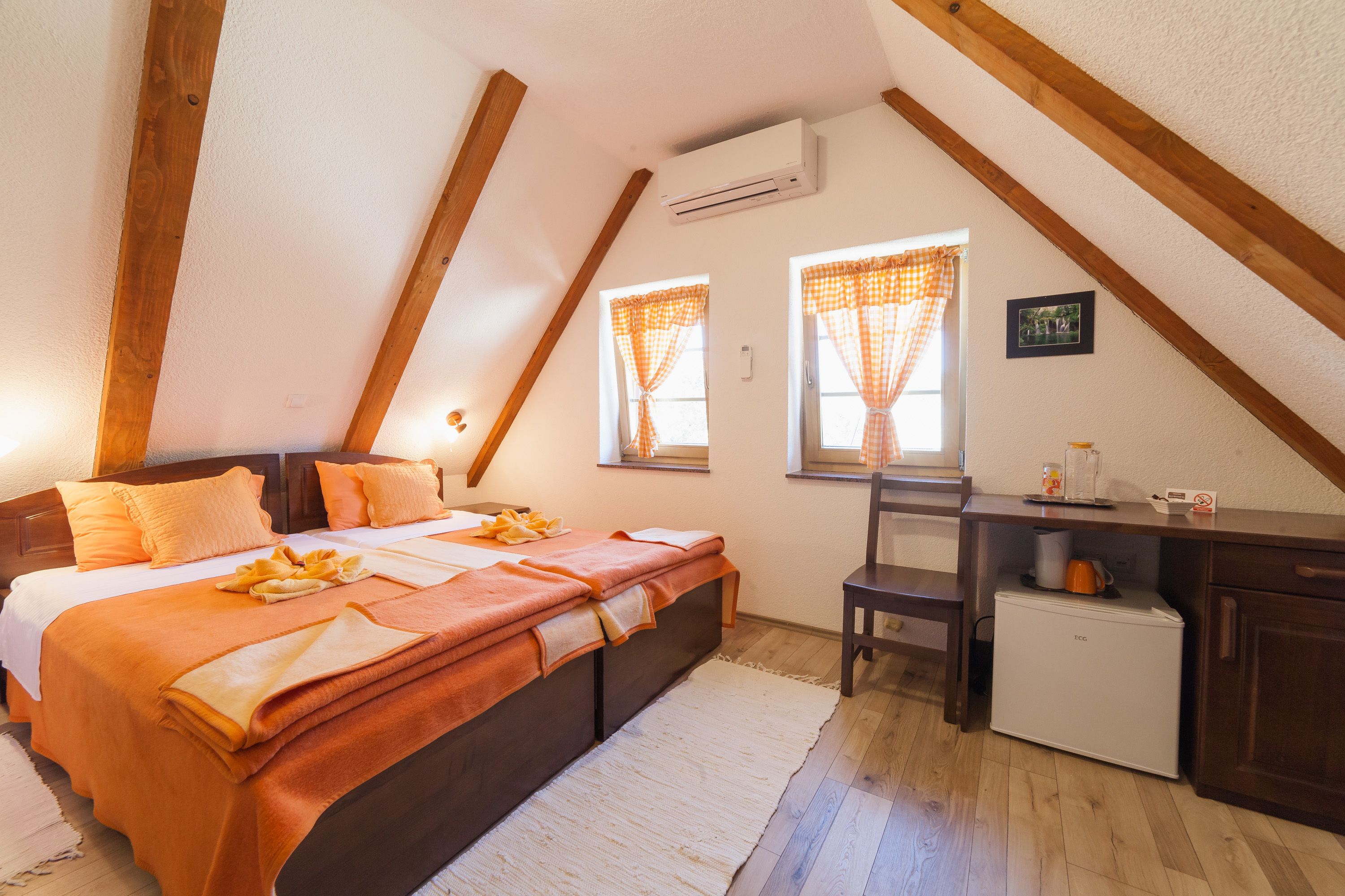 A bedroom with a bed, a desk, and a small refrigerator.