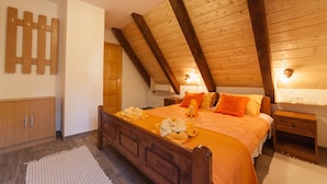 A bedroom with a wooden ceiling, a bed with orange bedding, a nightstand, and a wooden wardrobe. - House Rustico (Plitvicka Jezera)