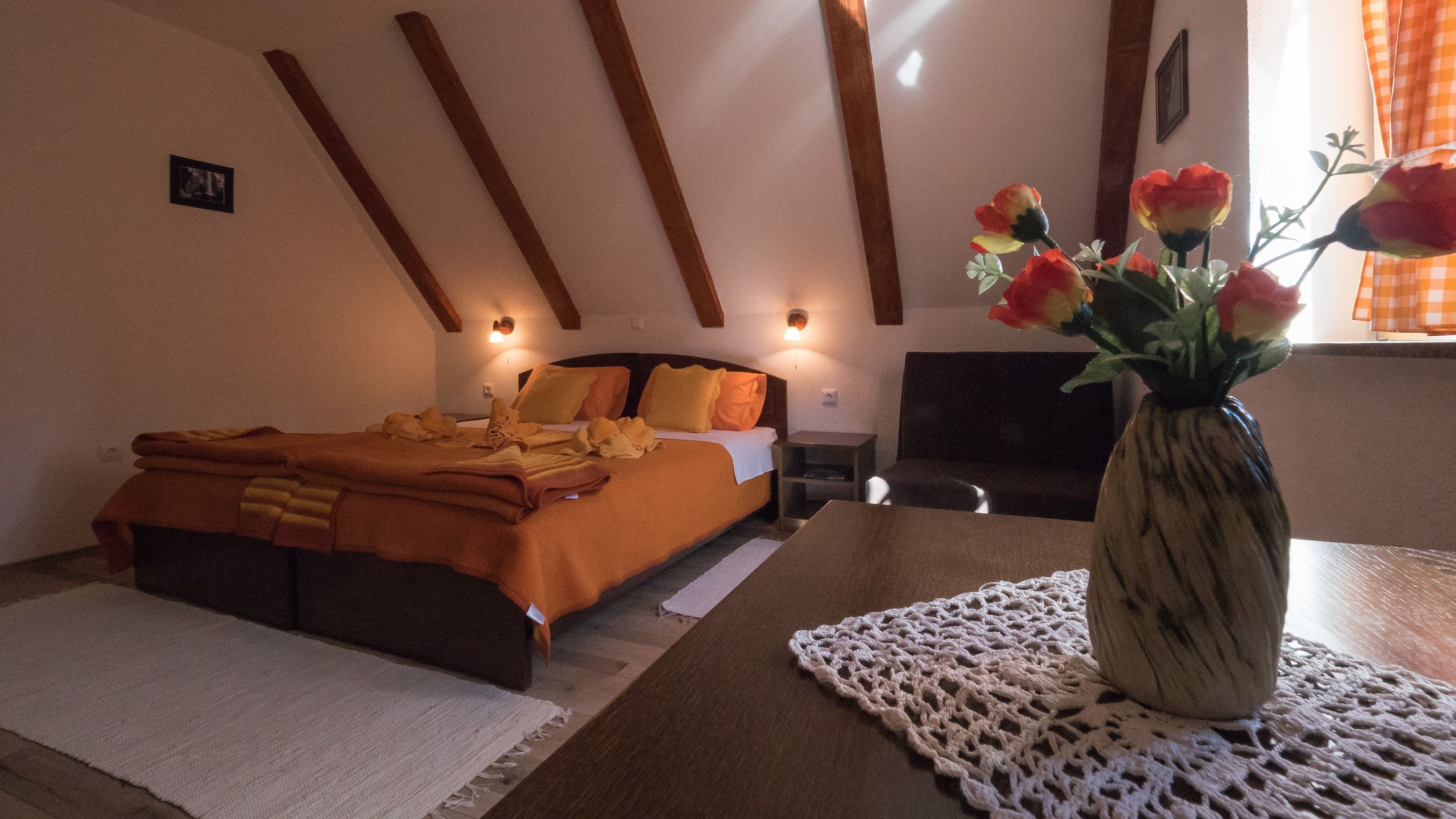 A bedroom with a bed, bedside tables, a vase with flowers, and a fireplace.