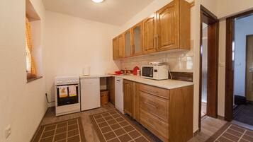 A compact kitchen with wooden cabinets, a microwave, a small oven, and a dishwasher.