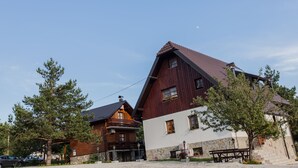 A traditional wooden building with a stone base, a sloped roof, and a small balcony with flowers. - House Rustico (Plitvicka Jezera)