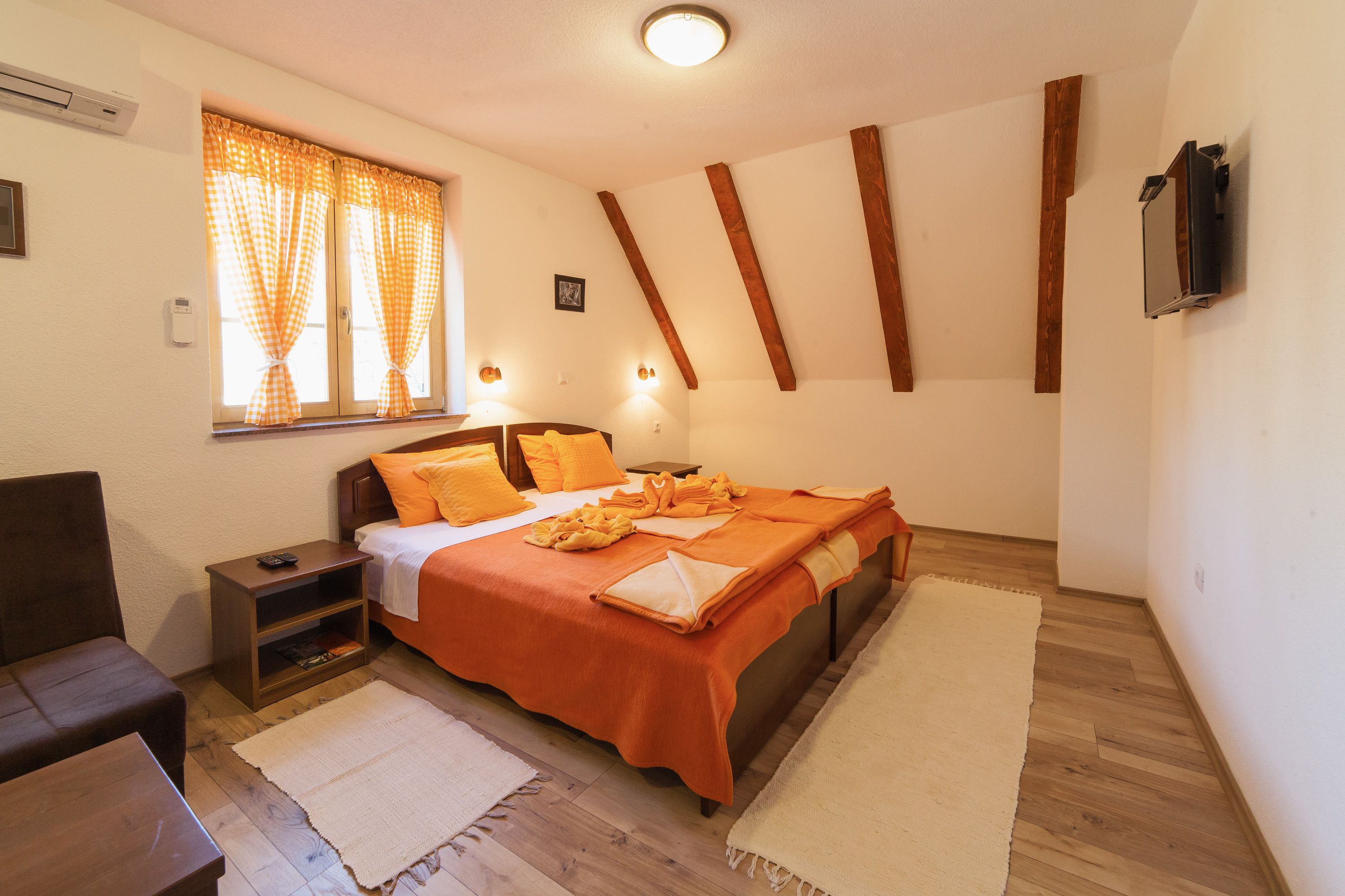 Un dormitorio con cama, mesita de noche y televisión instalada en la pared.