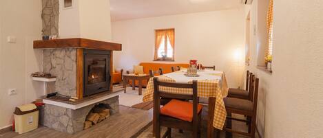 Un comedor con chimenea de piedra, mesa de madera y sillas.