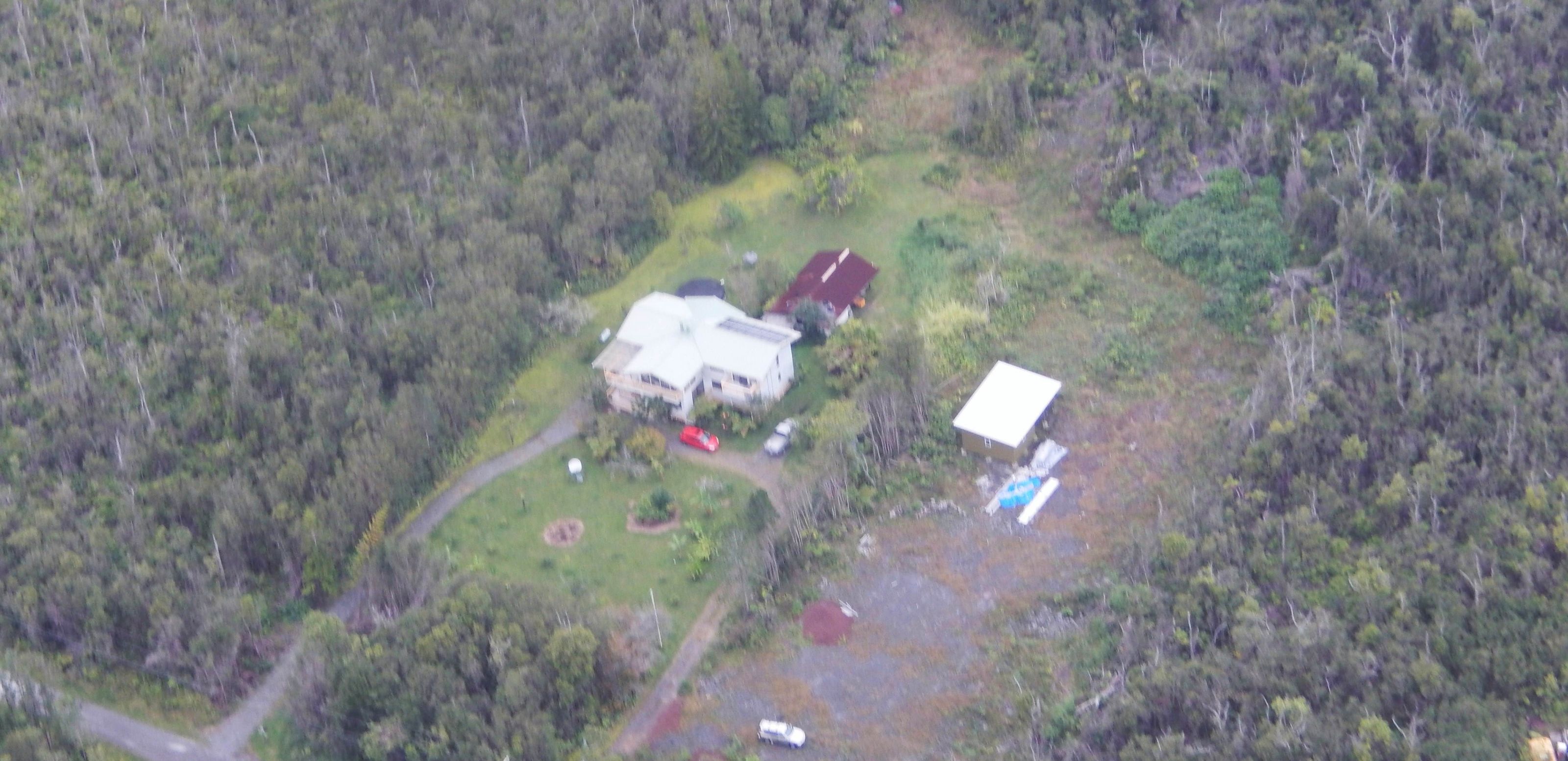 Luchtbeeld van een pand met een groot huis, een kleiner gebouw en een omheind gebied.