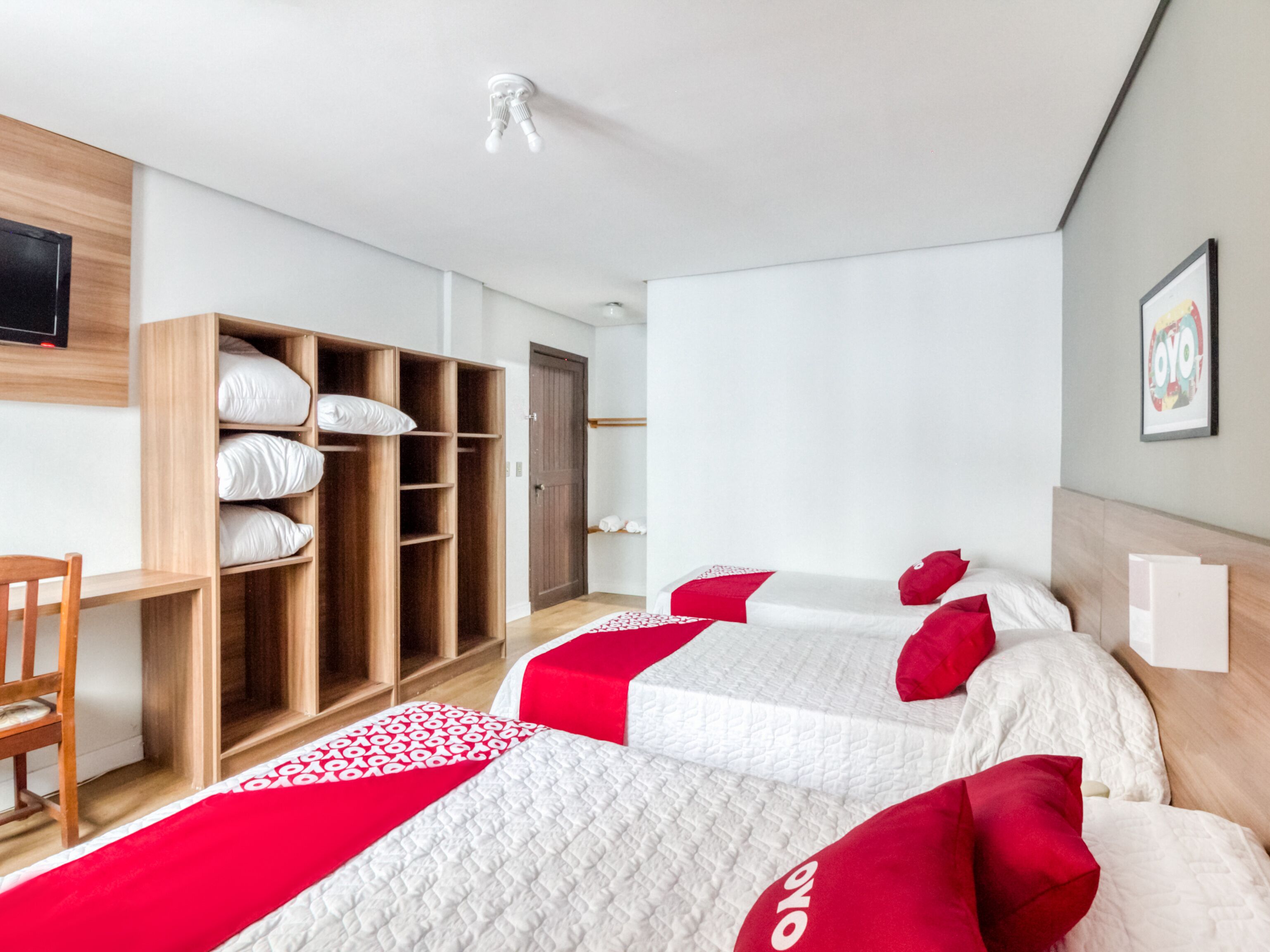 Una habitación de hotel con dos camas, un armario de madera, un escritorio y una silla.