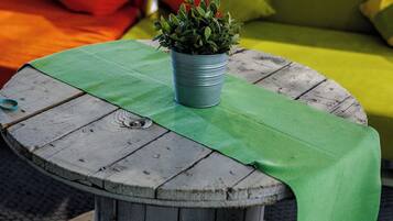 Una mesa redonda de madera con un mantel verde y una planta en maceta encima.