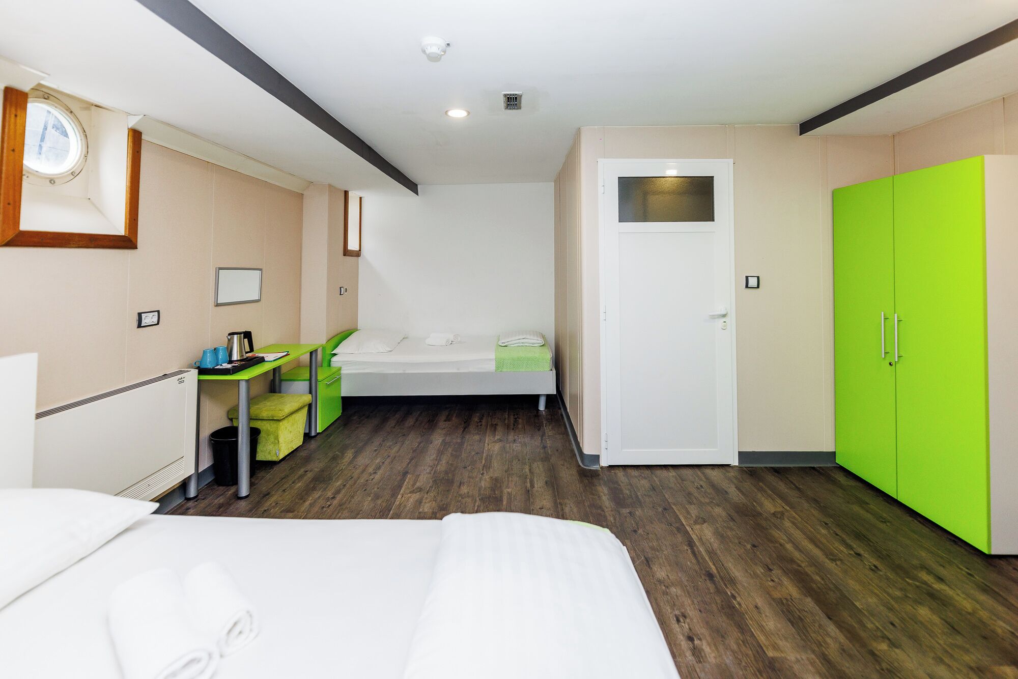 Una habitación de hotel con una cama, un escritorio, una silla, un armario y una ventana.