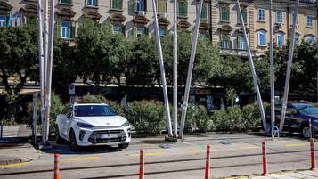 Un auto blanco estacionado en una calle con edificios al fondo.