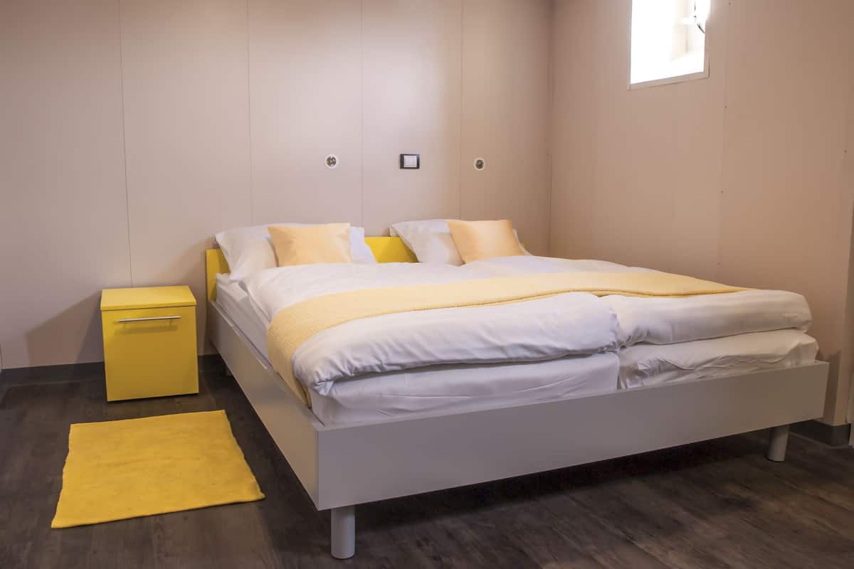 A modern bedroom with a bed, a bedside table, and a small yellow rug.