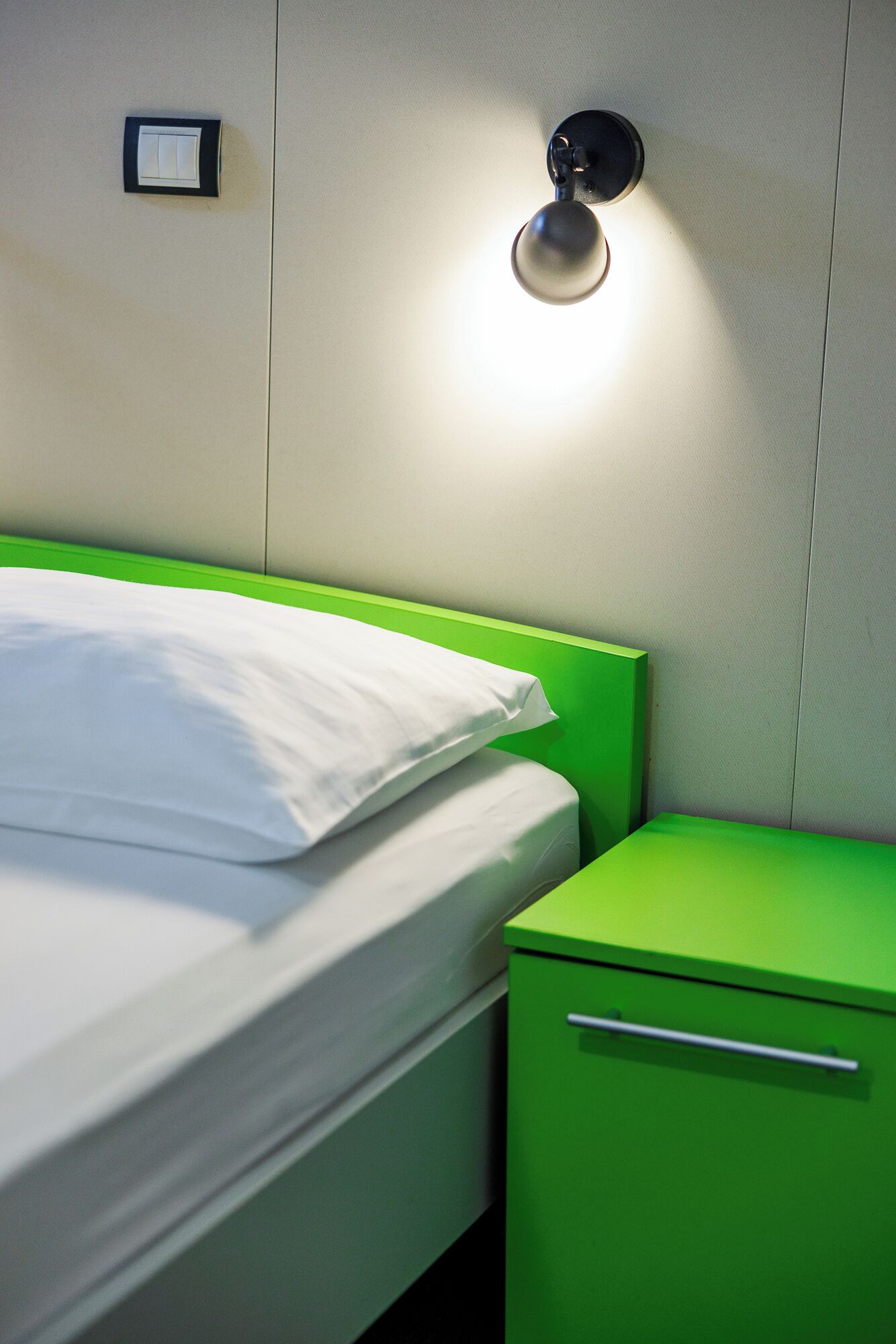 Una cama con cabecera y mesita de noche verdes.