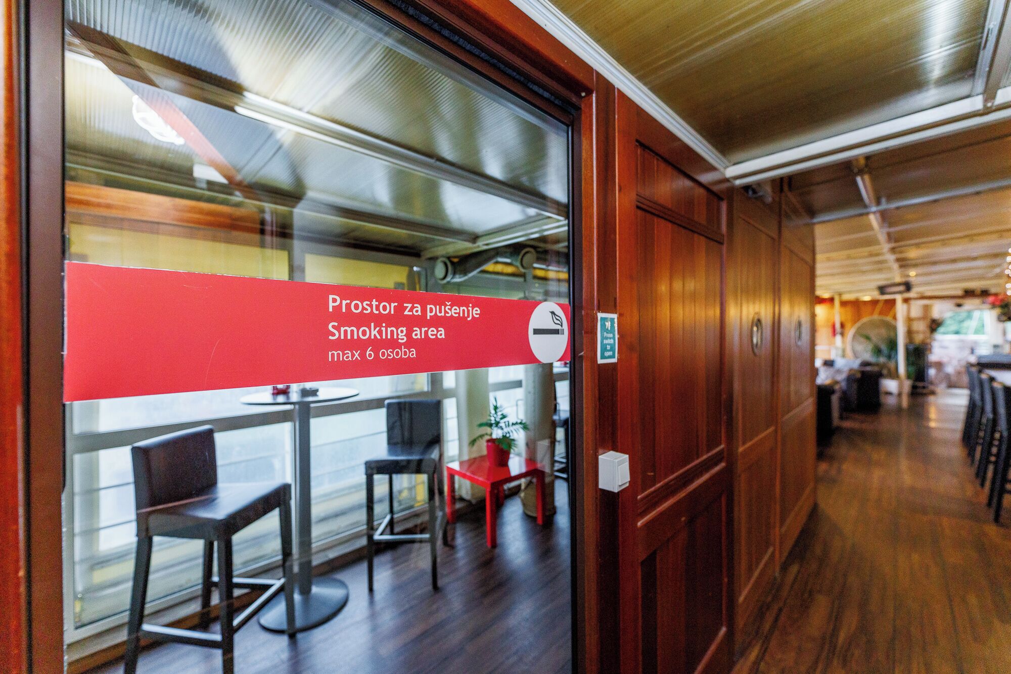 Un espace restaurant signalé par un panneau rouge indiquant qu’il s’agit d’un espace fumeurs et que le nombre maximal de personnes autorisées est de six.