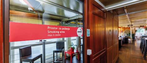 Un espace restaurant signalé par un panneau rouge indiquant qu’il s’agit d’un espace fumeurs et que le nombre maximal de personnes autorisées est de six.
