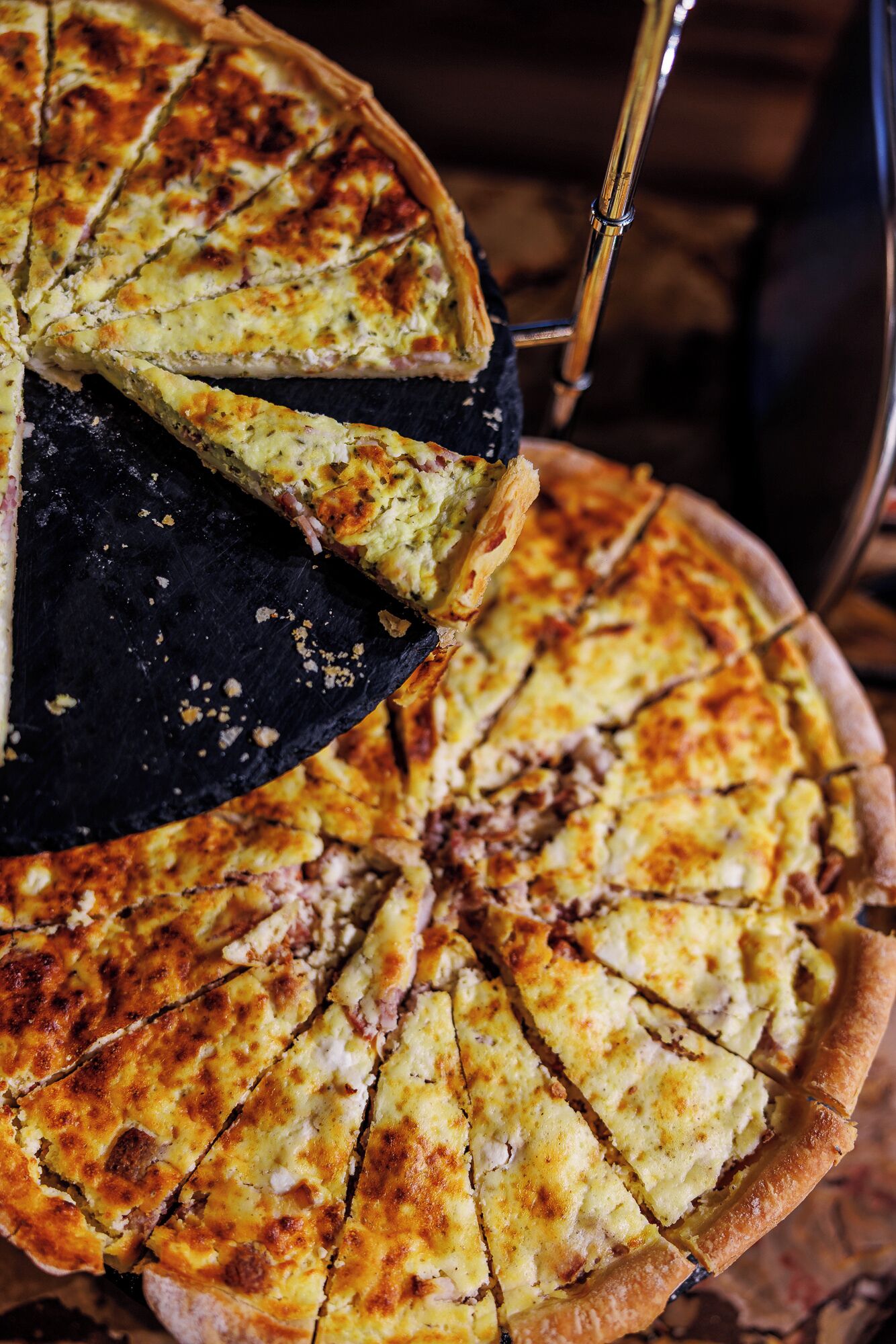 A pie with a golden-brown crust, sliced and served on a black plate.