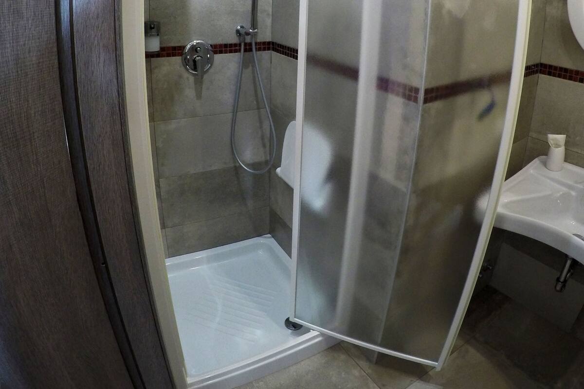 A modern bathroom with a glass shower enclosure, a white sink, and a tiled floor.