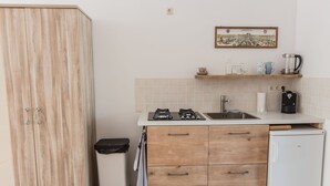A compact kitchen with a wooden cabinet, a sink, a coffee maker, and a small refrigerator. - Park43 (Haarlem)