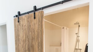 A bathroom with a shower, toilet, and a wooden sliding door. - Park43 (Haarlem)