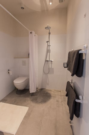 Un baño moderno con ducha, inodoro y barra para toallas.