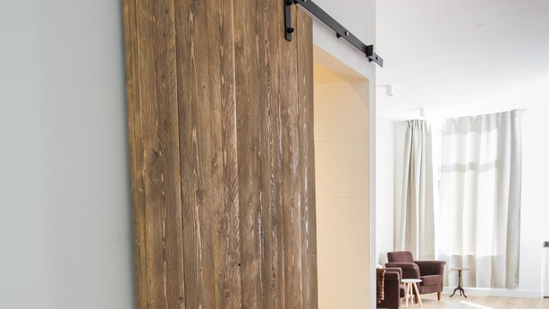 A room with a wooden sliding door, a bed, a chair, and a lamp. - Park43 (Haarlem)