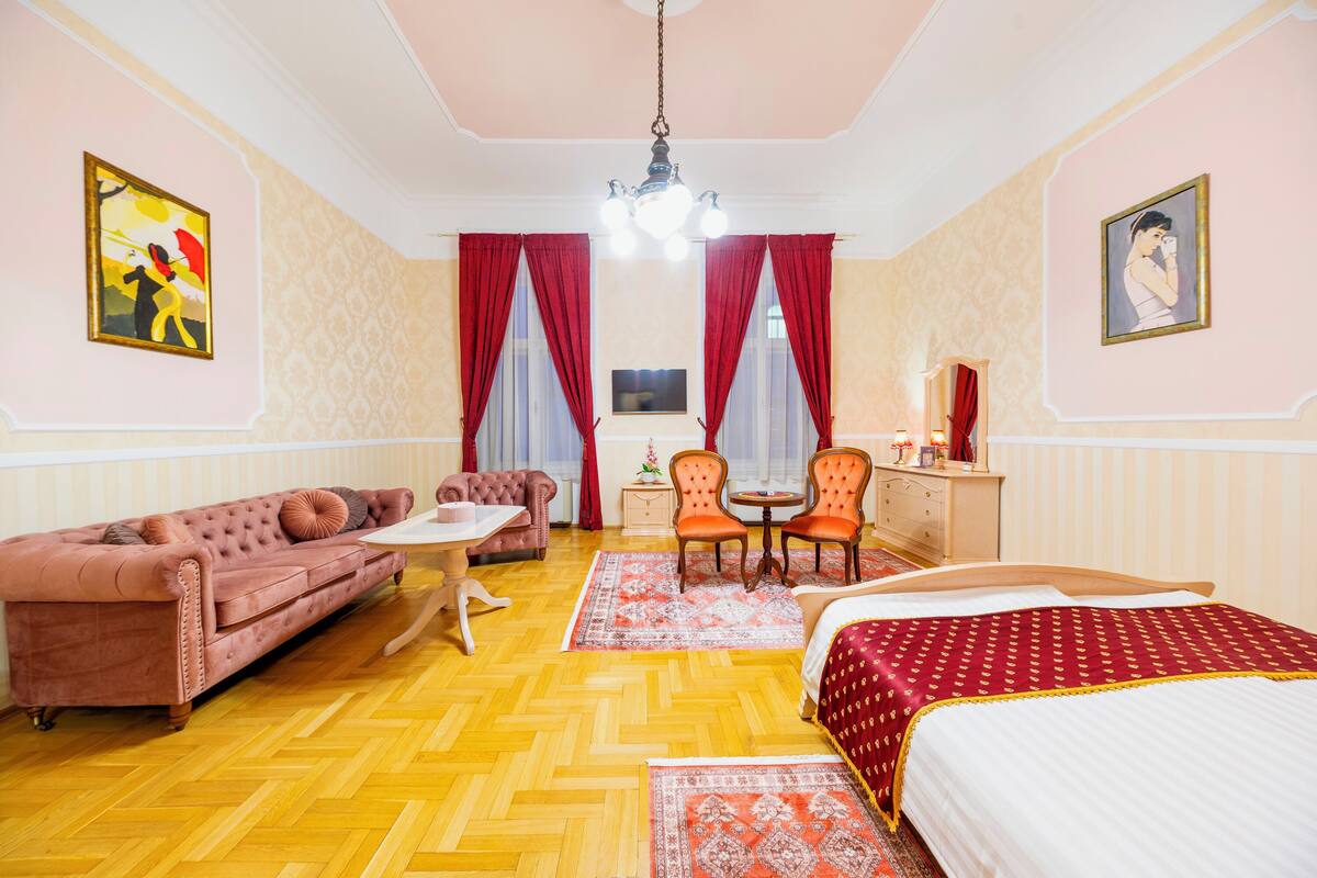 Una habitación con sofá, cama, escritorio y dos sillas.