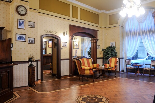 Un vestíbulo con piso de madera, un candelabro y una mesa de recepción.