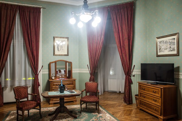 Une pièce comprenant une commode en bois, un téléviseur, une table avec des chaises et un lustre.