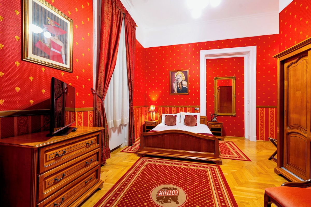 Una habitación con cama, cómoda y televisor sobre un mueble.