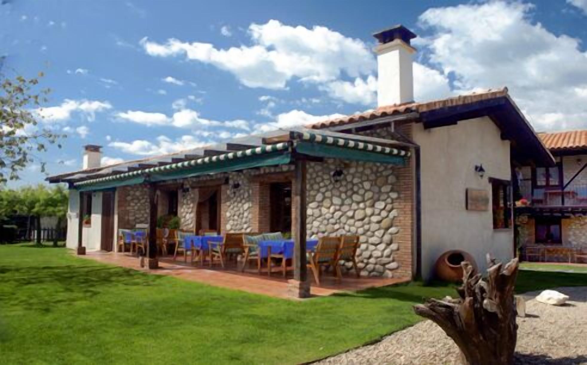 A stone building with a covered patio, outdoor seating, and a well-maintained lawn.