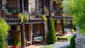 Un edificio de varios pisos con zonas de estar al aire libre, plantas en macetas y una pared de piedra.
