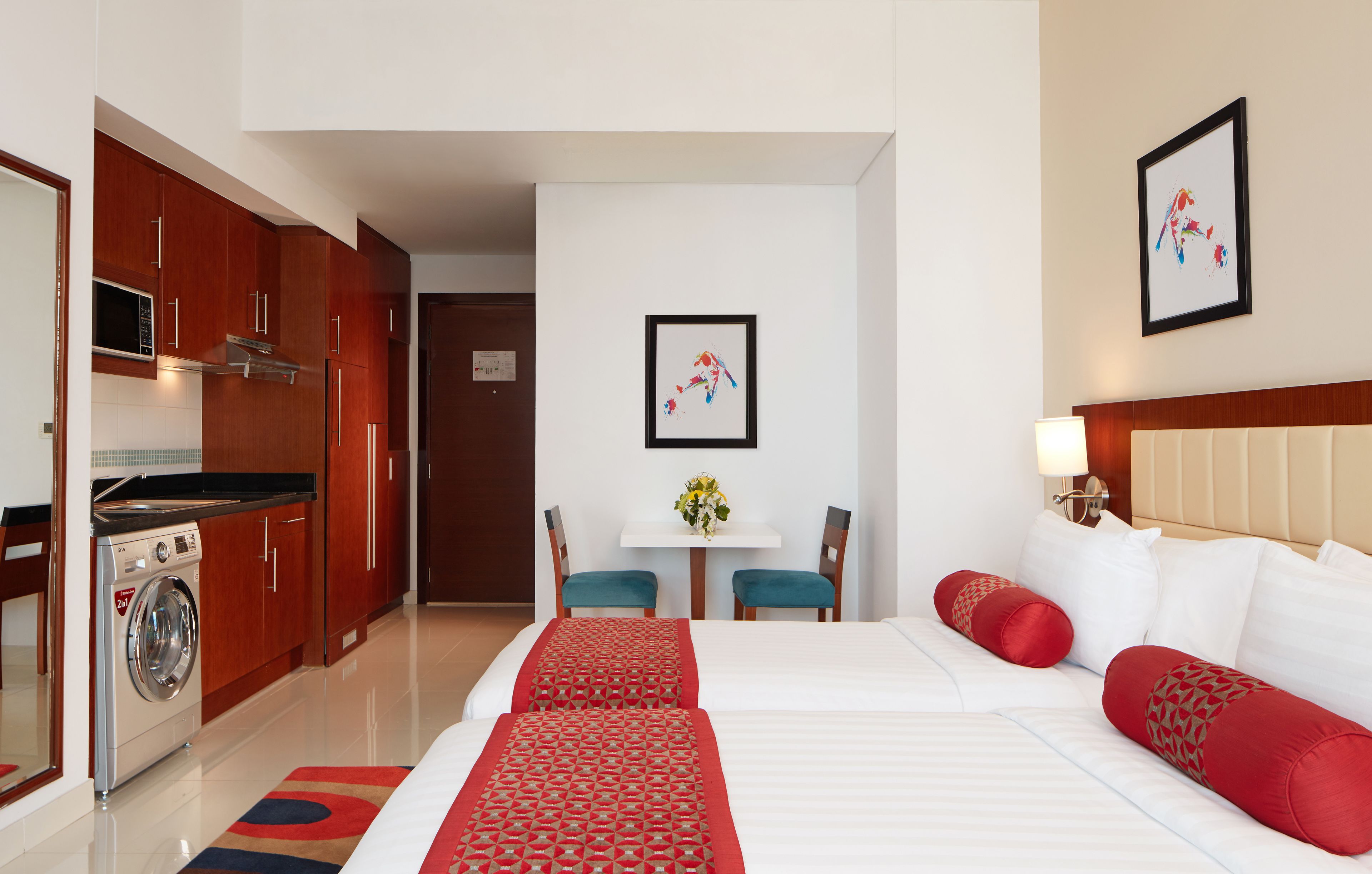 Une chambre d’hôtel équipée d’un lit, d’un bureau, d’une chaise, d’une machine à laver et d’une table à manger.