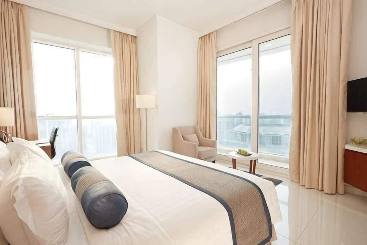 A hotel room with a large bed, a desk, a chair, and a TV.