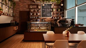 Een gezellig café met een prikbord, houten meubels en planken met potten en flessen.
