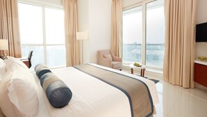 Een hotelkamer met een groot bed, een stoel, een klein tafeltje en uitzicht op de stad.