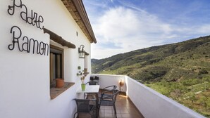 Un balcon avec une table et des chaises, un pot de fleurs et une pancarte sur laquelle on peut lire « Padre Ramon ».