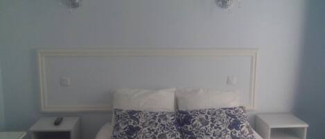 A bedroom with a bed, two bedside tables, and wall-mounted lamps.
